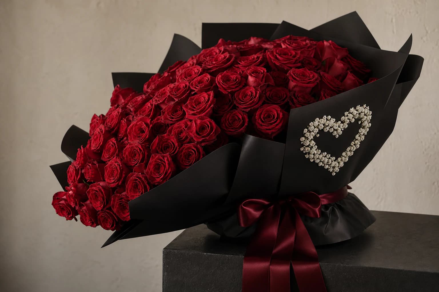 Large red rose bouquet in black wrapping with a white floral heart detail