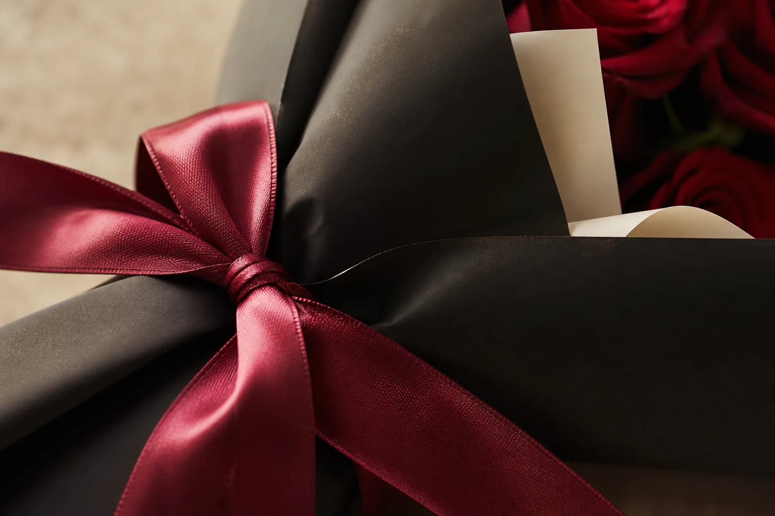 Garnet satin ribbon tied around layered florist wrapping